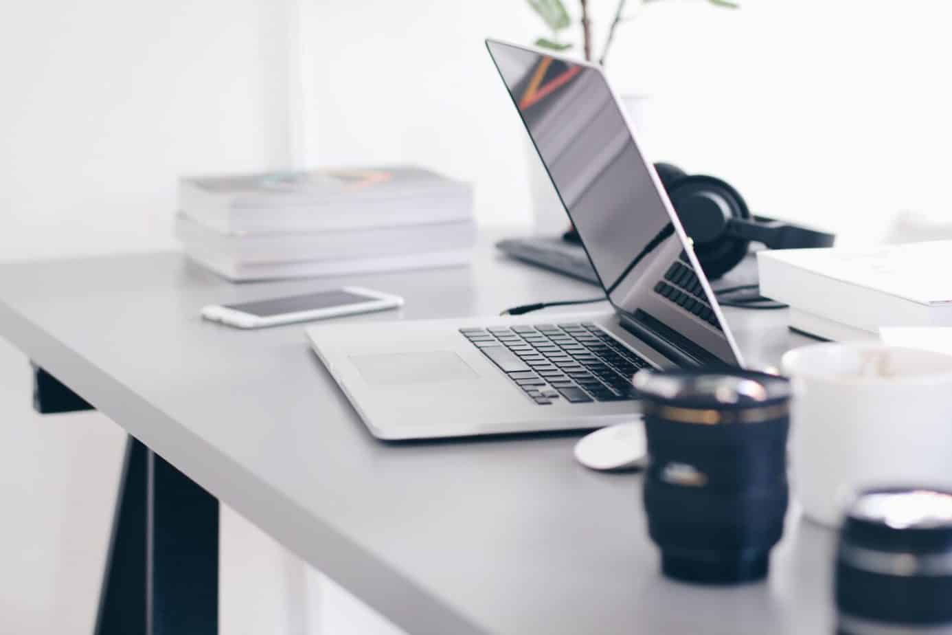 silver MacBook Pro on a white table with camera lens