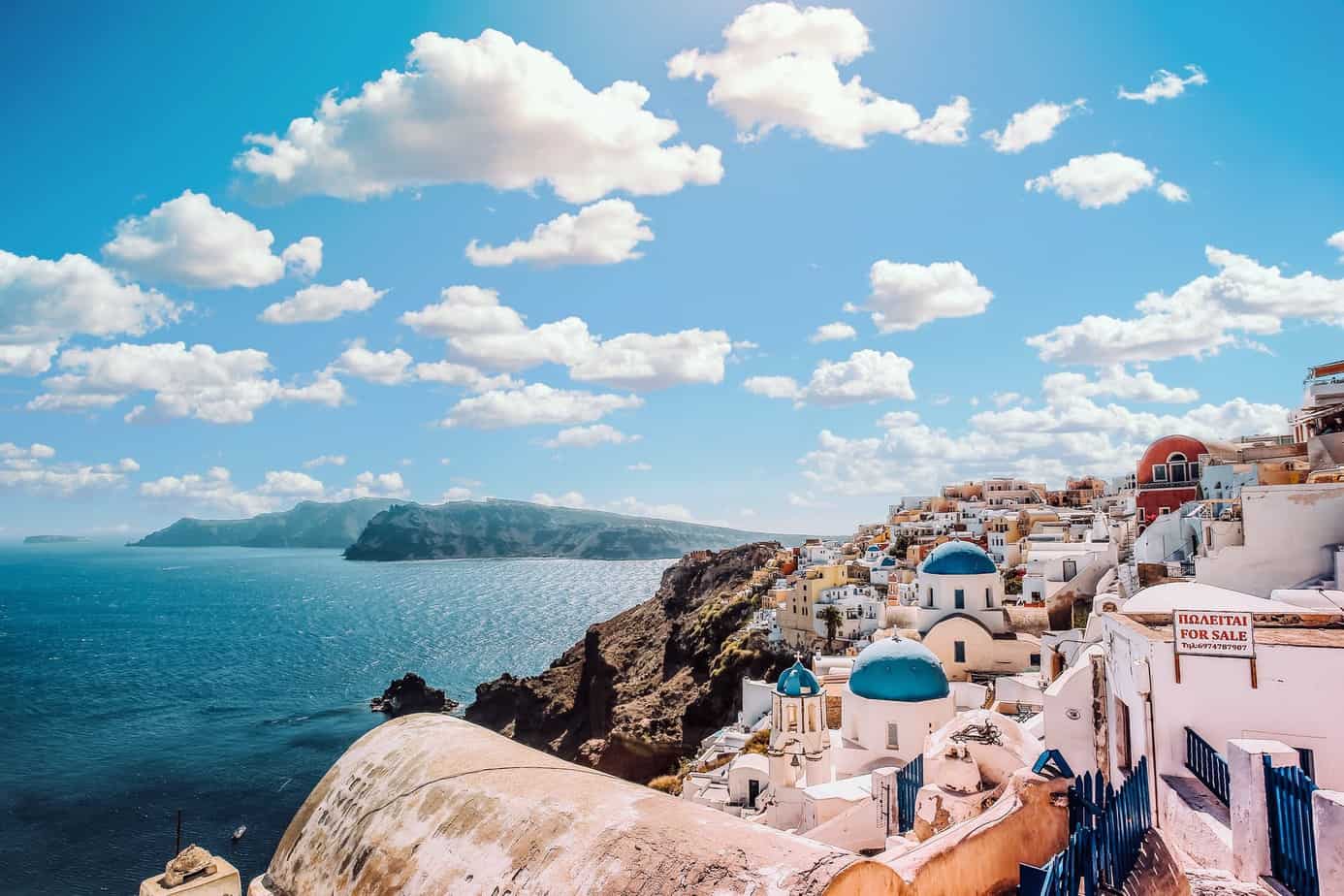 4 Tips For Planning Your Next Tour in Greece | white concrete house near body of water under white and blue cloudy sky