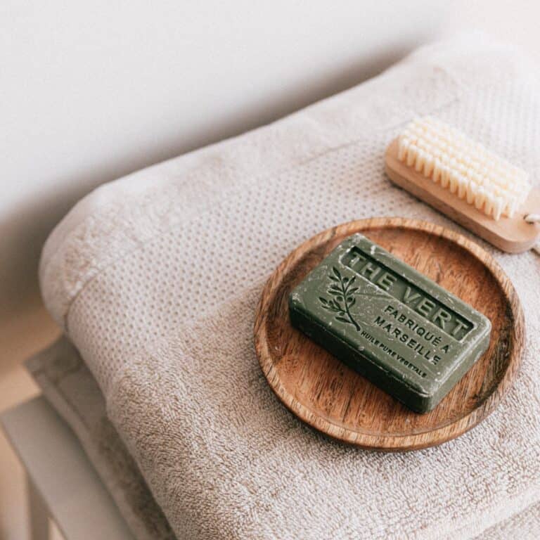 6 Practical bathroom swaps for sustainable living | natural soap and brush on folded towels