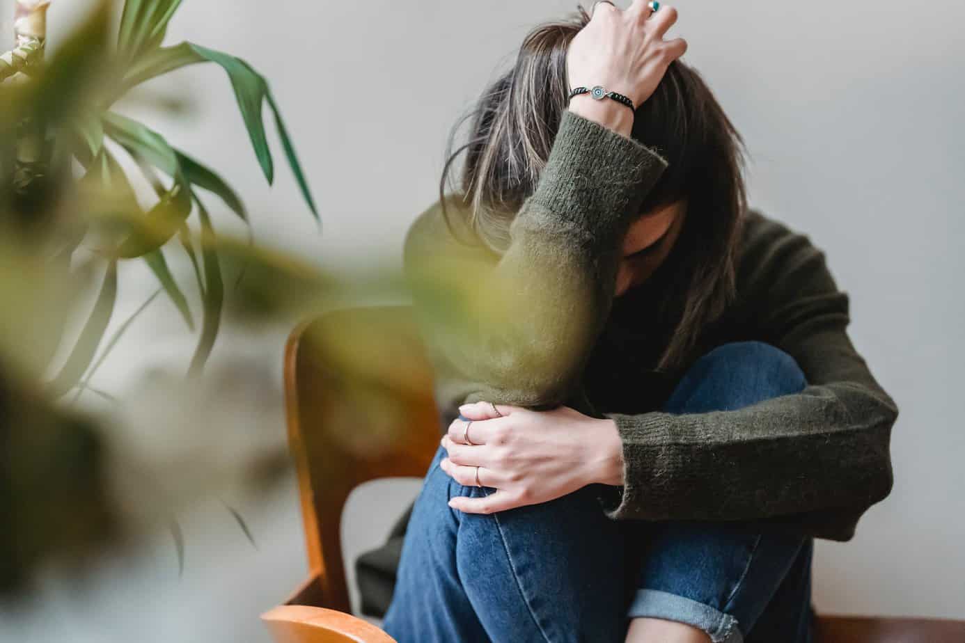 Spotting the common signs of anxiety and what to do - unrecognizable upset lady embracing knees sitting on chair