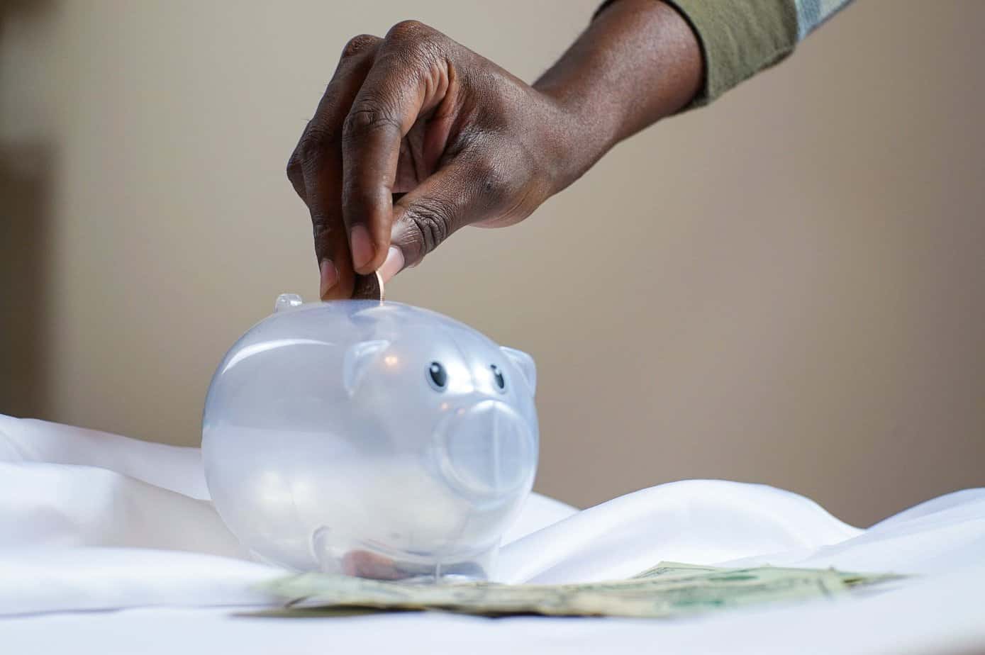 Positive lifestyle changes that will pack a punch - person putting coin in a piggy bank