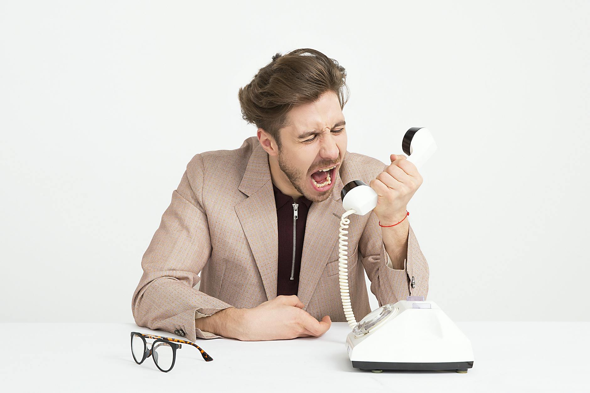 man wearing brown suit jacket mocking on white telephone - Why could you be feeling depressed?