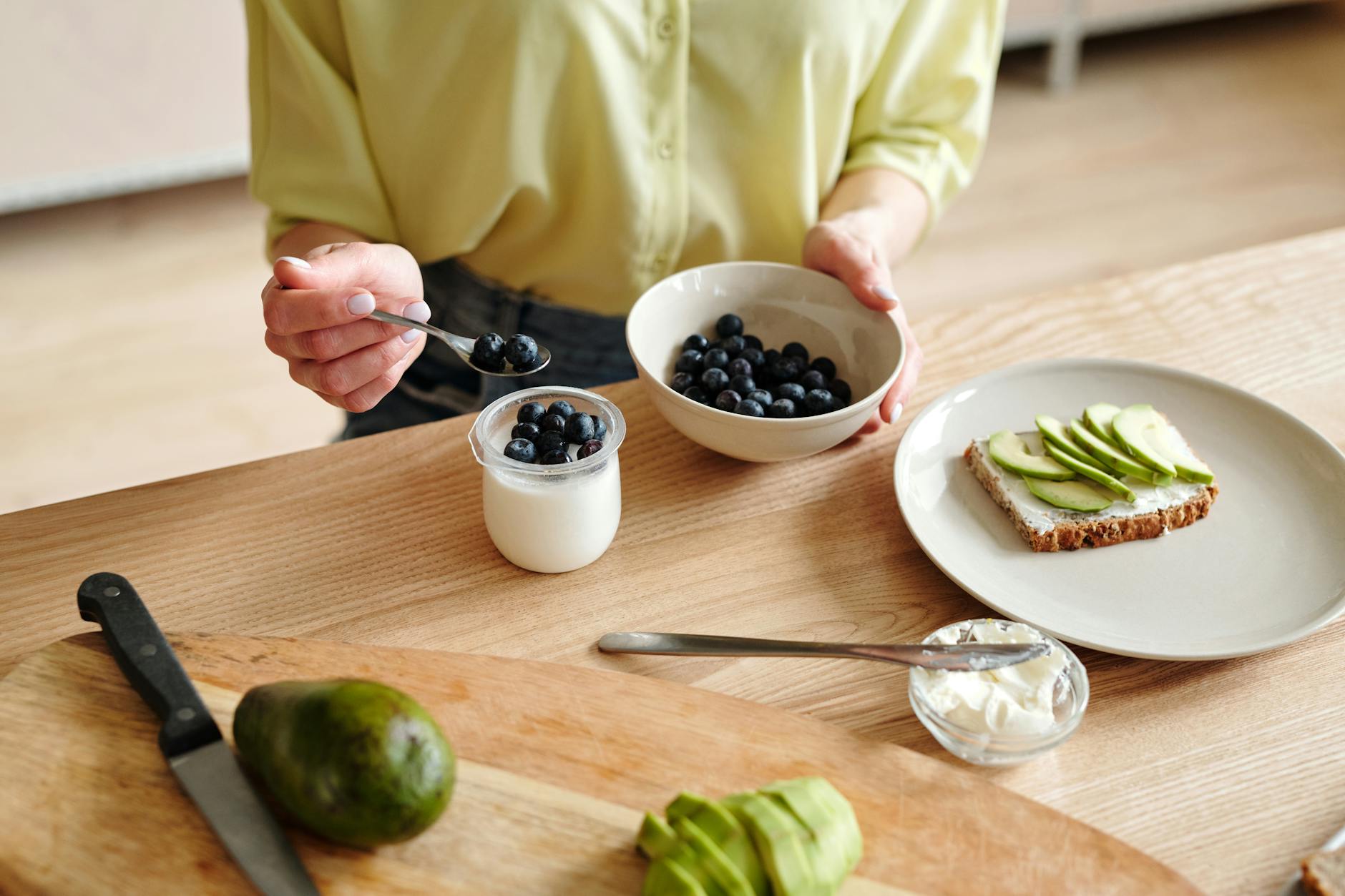 person putting blueberries on yogurt - Ways To Improve Your Lifestyle And It’s Easier Than You Think