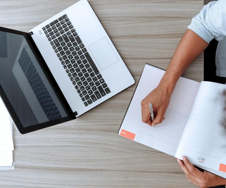 person holding white paper on brown wooden table