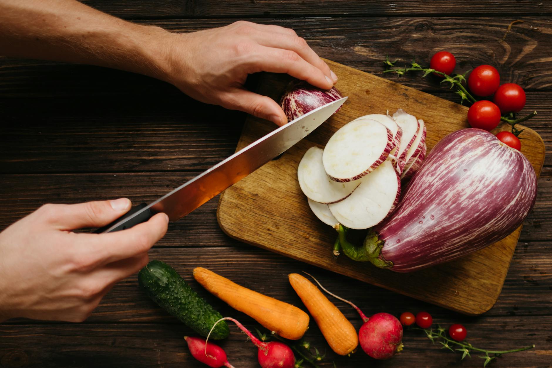 person slicing white onion on brown wooden chopping board