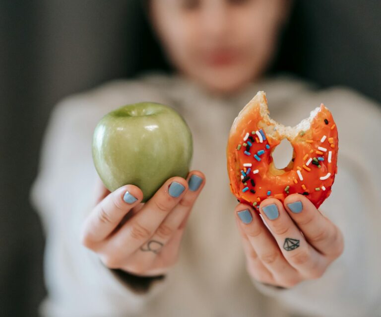 woman showing apple and bitten doughnut